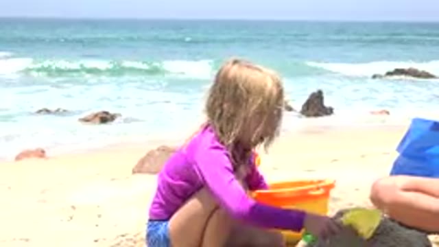 CABO SAN LUCAS MEXICO-2019: Girl Wearing Purple Shirt Plays In Sand With Woman