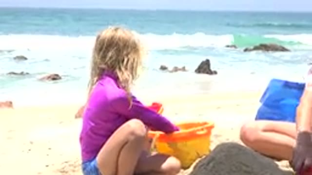 CABO SAN LUCAS MEXICO-2019: Girl Wearing Purple Shirt Plays With Yellow Beach Bucket