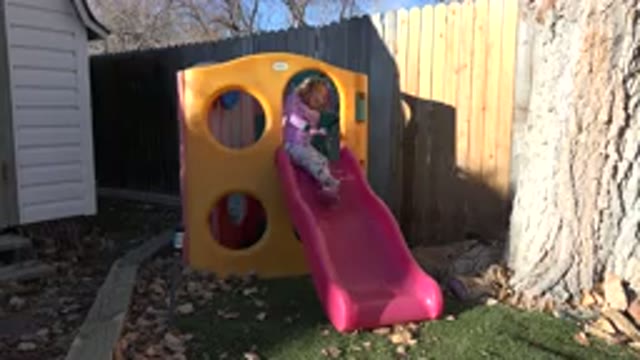 WESTMINSTER COLORADO-2019: Child Positioning Herself On A Slide In A Backyard