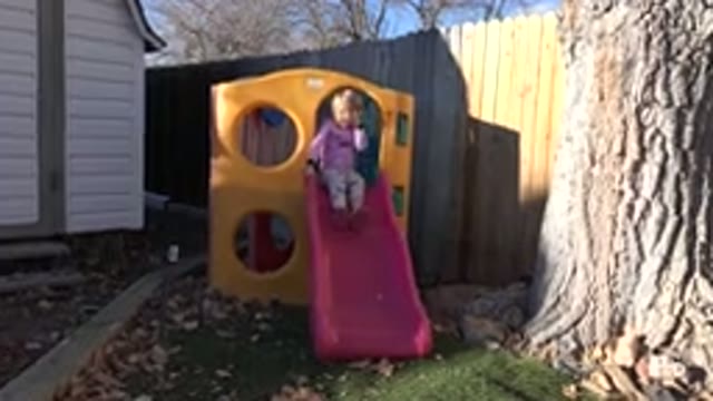 WESTMINSTER COLORADO-2019: Kid Sitting On A Yellow And Pink Plastic Slide In The