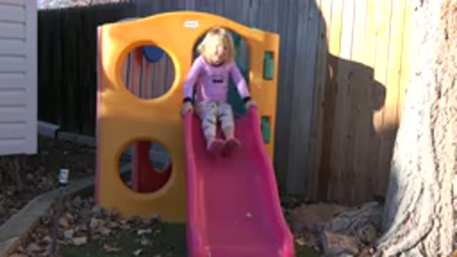 WESTMINSTER COLORADO-2019: Young Girl Playing on Pink Slide in Backyard