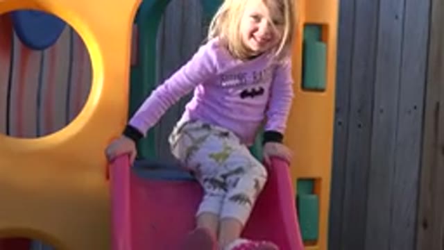 WESTMINSTER COLORADO-2019: Girl Wearing Pink Shirt Sits On Red Slide Of Yellow