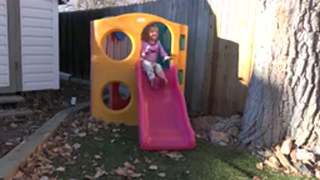 WESTMINSTER COLORADO-2019: Little Blonde Girl Playing and Slipping on the Slide in Yard