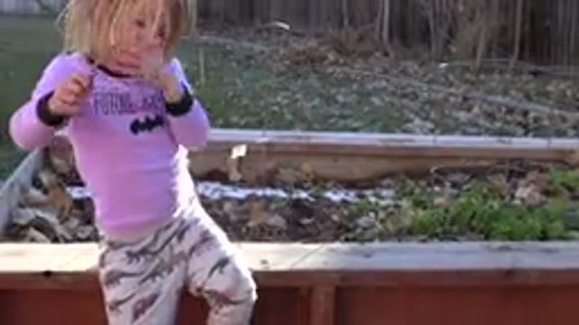 WESTMINSTER COLORADO-2019: Girl Wearing Pink Shirt Sits On Redwood Bench On A Sunny Day