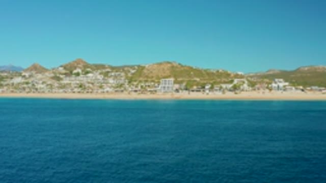 BUZZARDS EAST CAPE LOS CABOS BCS MEXICO-2022: Sandy Beach and Coastal Resort with Hills Beyond