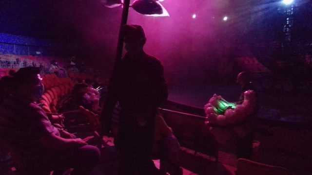 SAN JOSE DEL CABO BCS MEXICO-2022: Man with Light Pole Moving Through Seated Club Audience