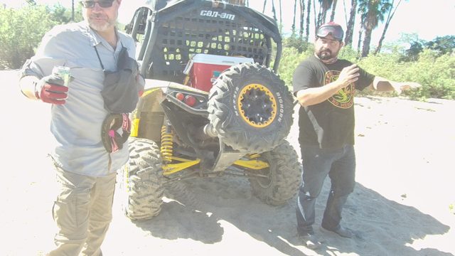 LOS CABOS BCS MEXICO-2022: Two Men Interacting Beside Off-road Vehicle on Sandy Terrain