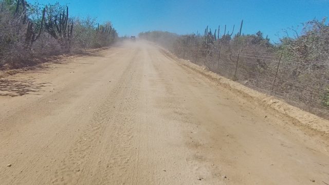 LOS CABOS BCS MEXICO-2022: Dusty Dirt Road with Vehicle Moving Through Arid Terrain