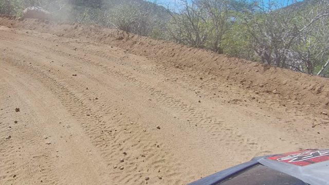 LOS CABOS BCS MEXICO-2022: Dusty Dirt Road with Vehicle Moving Through Hilly Landscape