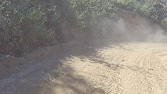 LOS CABOS BCS MEXICO-2022: Dust Cloud on Winding Dirt Road Through Rocky Terrain
