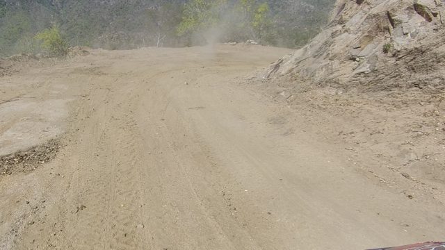 LOS CABOS BCS MEXICO-2022: Vehicle Moving on a Dusty Dirt Road Through Hilly Terrain