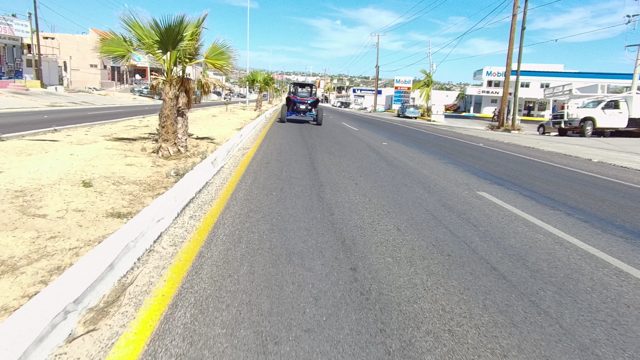 LOS CABOS BCS MEXICO-2022: Vehicle Traveling on a Road with Palm Trees and Buildings