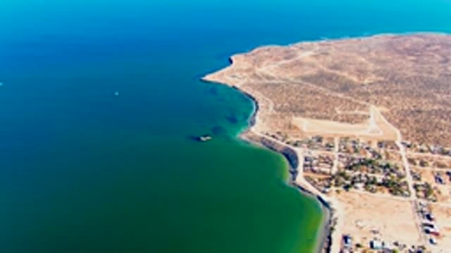 SAN JUANICO BCS MEXICO-2022: Coastal Shoreline and Moving Boat in Clear Water