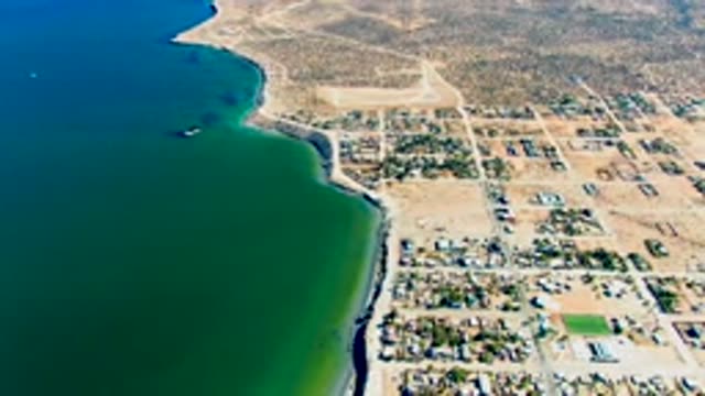 SAN JUANICO BCS MEXICO-2022: Coastal Town and Moving Boat Along Sandy Shore
