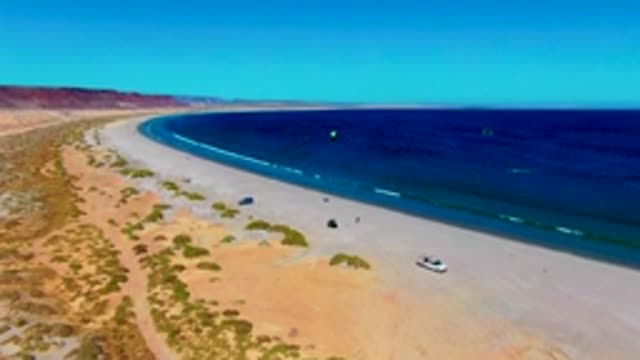 SAN JUANICO BCS MEXICO-2022: Kitesurfers Gliding Along a Coastal Desert Beach