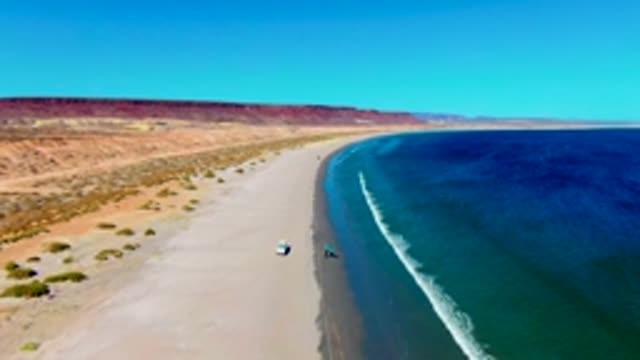 SAN JUANICO BCS MEXICO-2022: Kite Surfer and Vehicle Moving Along Desert Beach