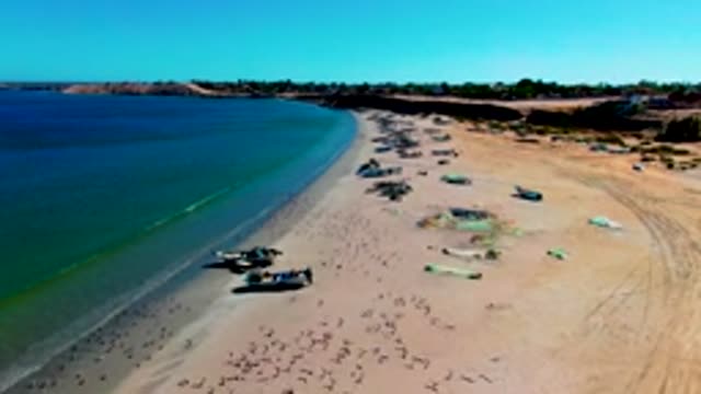 SAN JUANICO BCS MEXICO-2022: Waves Rolling Onto Sandy Beach with Fishing Boats
