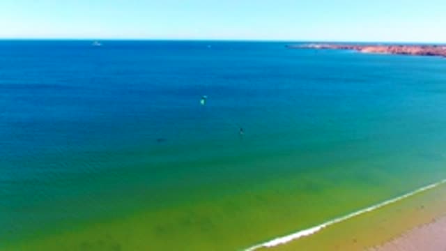 SAN JUANICO BCS MEXICO-2022: Kite Surfers Gliding over Turquoise Ocean near Sandy Shore