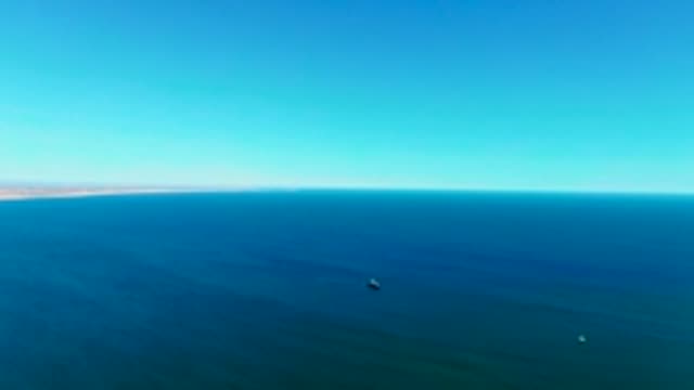 SAN JUANICO BCS MEXICO-2022: Ocean Surface with Distant Shore and Small Vessels
