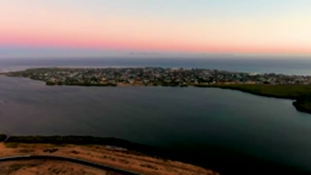 SAN CARLOS BCS MEXICO-2022: Vehicle Moving on Coastal Road near Town at Sunset