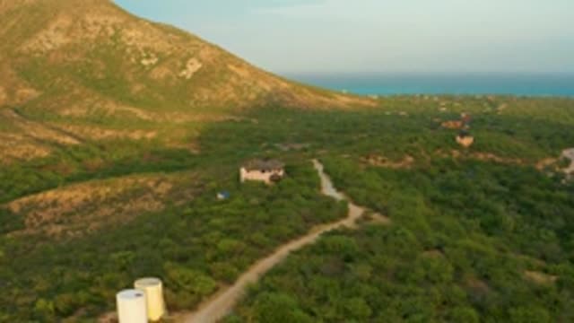 CABO PULMO LOS CABOS BCS MEXICO-2022: Dirt Road Winding Through Green Hills with Cylindrical Tanks