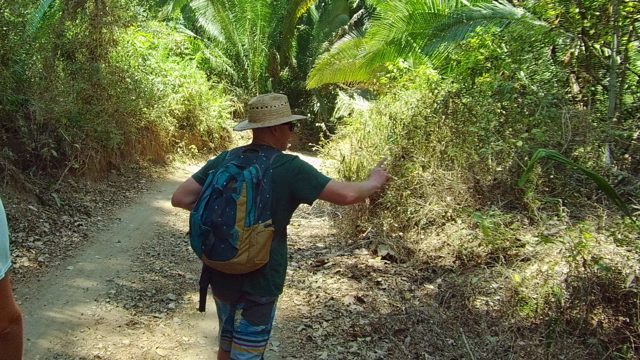 SAN PANCHO NAYARIT MEXICO-2022: Two Hikers Pointing at Vegetation on a Forest Trail