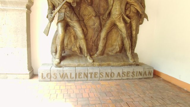 Bronze Statue with 'Los Valientes No Asesinan' Inscription