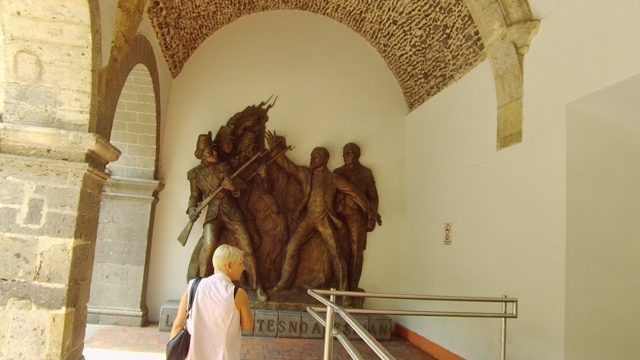 People Viewing Historical Relief in Arched Corridor