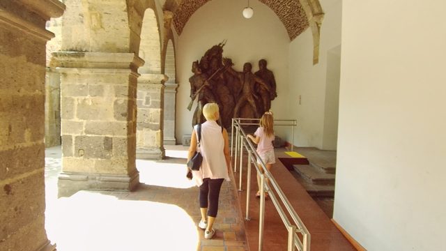 Woman and Child Walking Toward a Statue in a Stone Archway