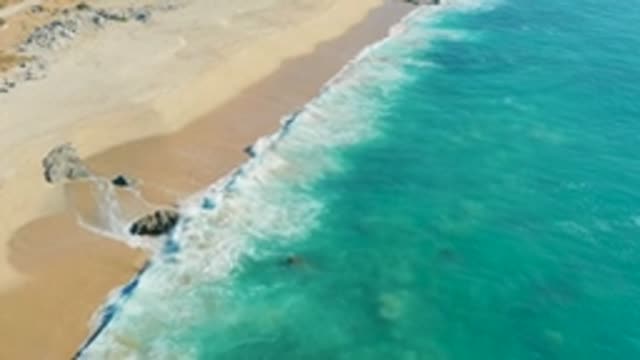 LA FORTUNA EAST CAPE BCS MEXICO-2022: Gentle Ocean Waves Rolling Onto Sandy Shore with Rocks