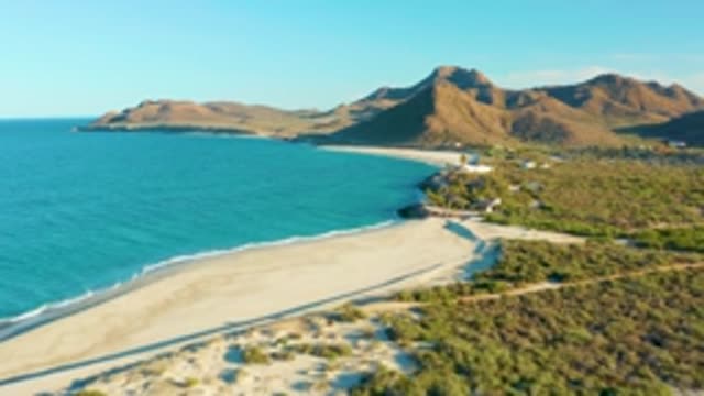 LAS BARRACAS EAST CAPE BCS MEXICO-2022: Sandy Beach with Ocean Waves and Mountain Backdrop