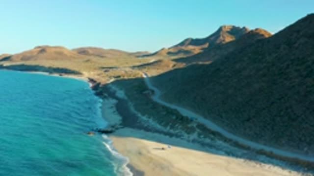 LAS BARRACAS EAST CAPE BCS MEXICO-2022: Coastal Road, Beach, and Mountains with Moving Vehicle and Person