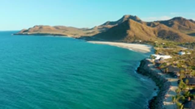 LAS BARRACAS EAST CAPE BCS MEXICO-2022: Gentle Ocean Waves Lapping at Rocky Shore with Distant Mountains
