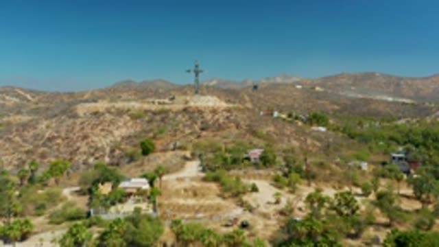 PUERTO LOS CABOS BCS MEXICO-2022: Aerial Pan of Hilltop Cross and Arid Terrain