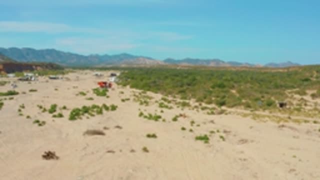 LOS FRAILES LOS CABOS BCS MEXICO-2022: Red Vehicle Moving Through Sandy Arid Landscape