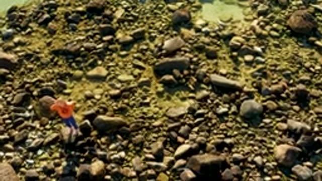 EL TULE LOS CABOS BCS MEXICO-2022: Person in Orange Shirt Walking Across River Rocks