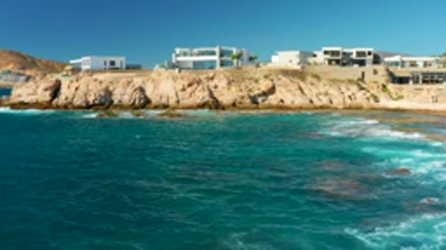 CHILENO BEACH LOS CABOS BCS MEXICO-2022: Waves Crashing Against Rocky Coastline With Cliffside Buildings
