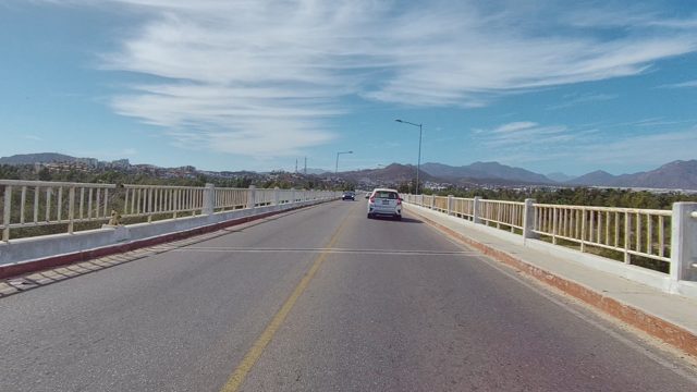 EAST CAPE LOS CABOS BCS MEXICO-2022: Vehicles and Scooter on a Bridge Road