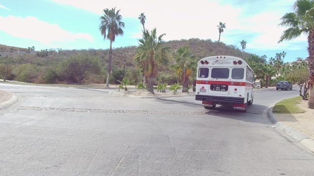 EAST CAPE LOS CABOS BCS MEXICO-2022: Bus Traveling on Palm Tree-lined Road Through Arid Hills