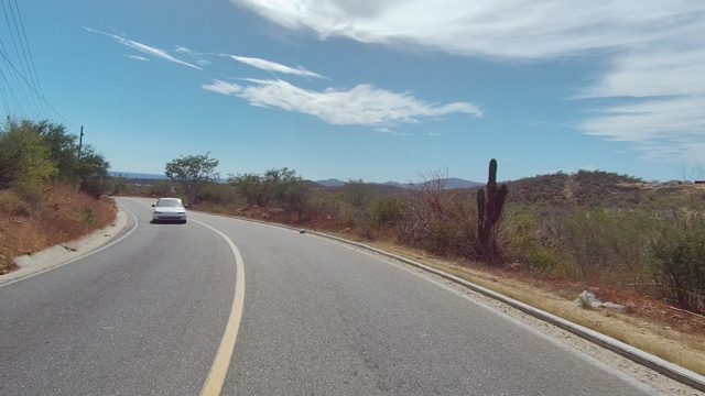 EAST CAPE LOS CABOS BCS MEXICO-2022: Winding Road Through Arid Landscape with Passing Car