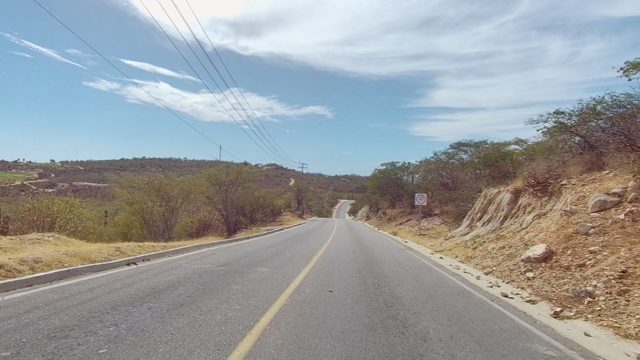 EAST CAPE LOS CABOS BCS MEXICO-2022: Two-Lane Road Through Arid Landscape with Scattered Trees