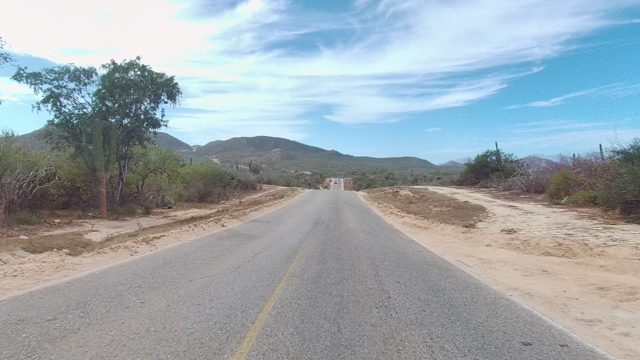 EAST CAPE LOS CABOS BCS MEXICO-2022: Vehicle Moving Along Desert Road with Distant Mountains