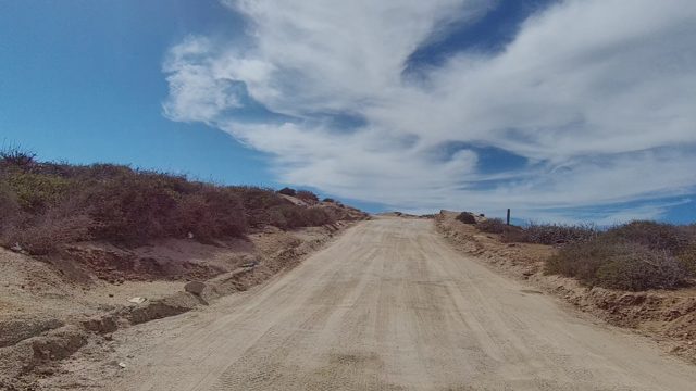 EAST CAPE LOS CABOS BCS MEXICO-2022: Dirt Road Through Arid Landscape with Sparse Vegetation