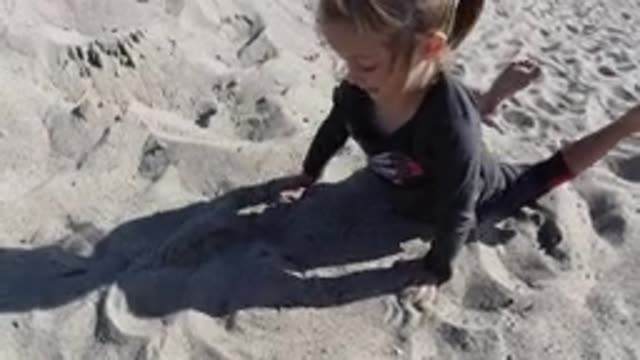 TRESTLES BEACH CALIFORNIA-2019: A Child Playing In The Sand Who At First Is Lying On Her Stomach