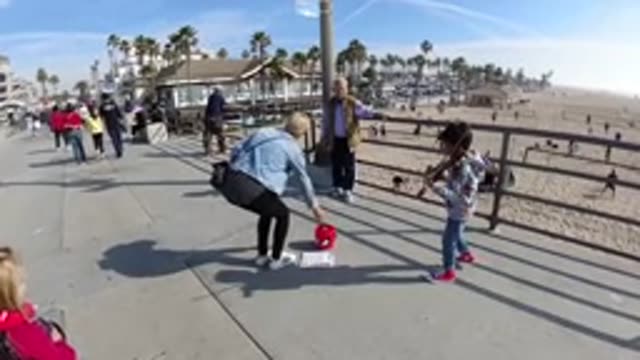 HUNTINGTON BEACH CALIFORNIA-2019: Woman Putting Money In A Bucket For A Little Violinist