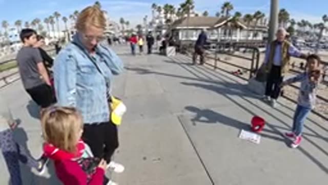 HUNTINGTON BEACH CALIFORNIA-2019: A Mother And Her Kid Being Entertained By A Violinist