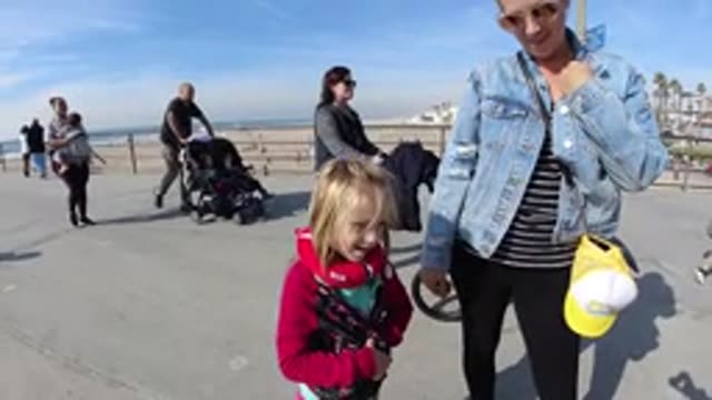 HUNTINGTON BEACH CALIFORNIA-2019: Woman Wearing Blue Jacket Stands With Small Child