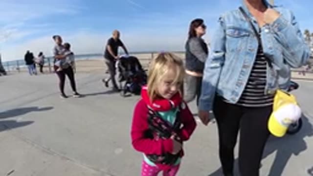 HUNTINGTON BEACH CALIFORNIA-2019: Young Girl in Pink Strolling on Beach with Adult
