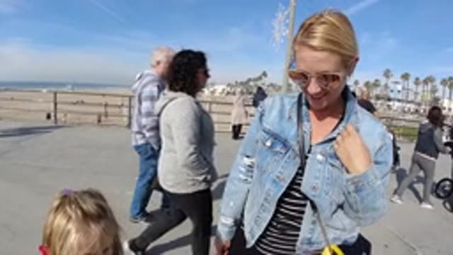 HUNTINGTON BEACH CALIFORNIA-2019: Woman Wearing Blue Coat Reaches Hand Up