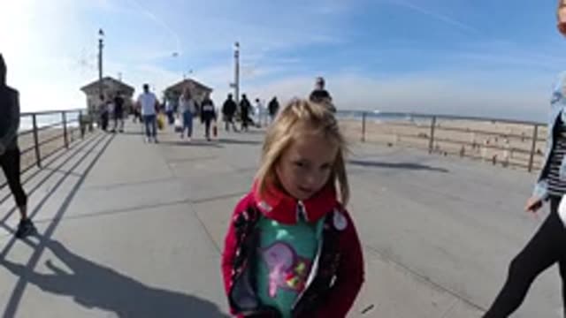 HUNTINGTON BEACH CALIFORNIA-2019: Little Girl Walking Backwards On A Pier Over A